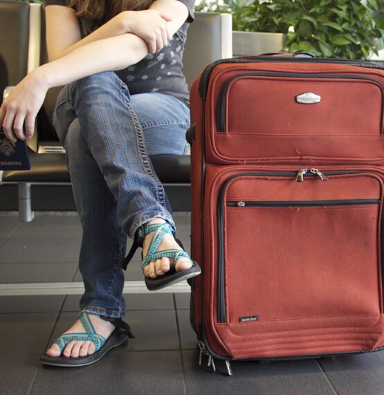 Traveller waiting beside a red suitcase
